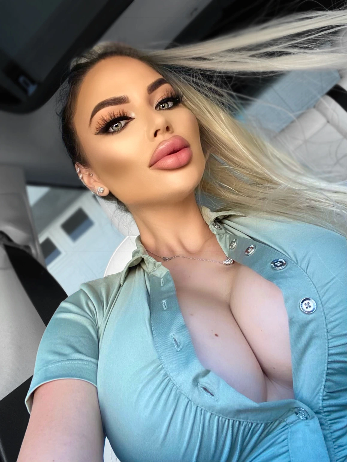 Sasha in a sage button-up shirt in the car, her long platinum hair caught by the wind.
