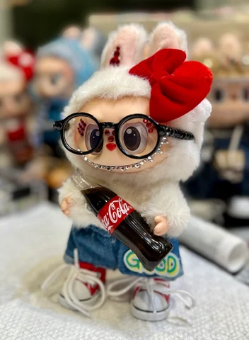Labubu Nº 10: a red bow, black glasses, a cola bottle and denim shorts.